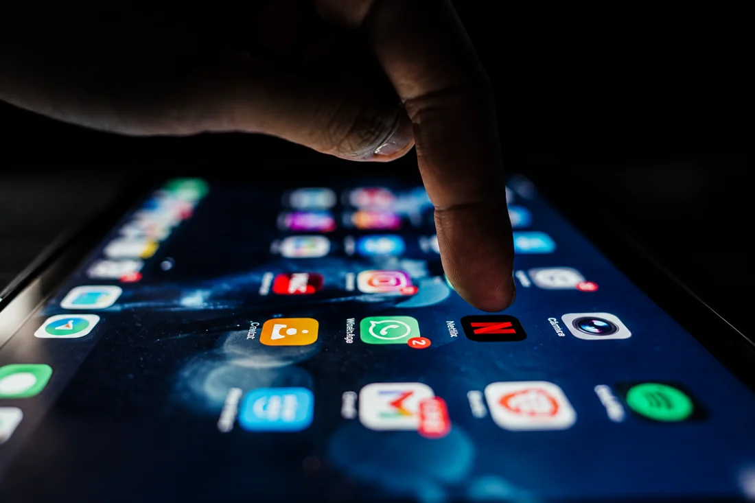 Dedo próximo ao aplicativo da Netflix na tela do celular